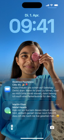 Fünf iPhone Modelle; jedes Modell überlappt leicht mit dem daneben; auf dem Display ganz links ist eine Unterhaltung mit einem Hintergrund in Nachrichten zu sehen; das zweite Display von links zeigt den Homescreen mit bunten App Symbolen; das mittlere Modell zeigt den Sperrbildschirm mit Foto, Ziffern für die Uhrzeit in Liquid Glass; zwei Benachrichtigungen erscheinen am unteren Displayrand; das zweite Modell von rechts zeigt transparente Liquid Glass App Symbole; das Modell ganz rechts zeigt den Musikplayer in Liquid Glass
