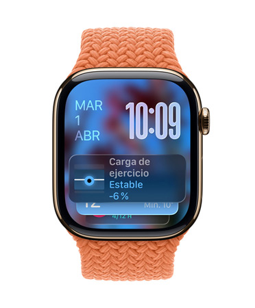 Un Apple Watch en oro rosa con correa trenzada en color mandarina muestra la fecha en la parte superior izquierda, la hora en la parte superior derecha con los números superpuestos y el widget de carga de ejercicio en la parte inferior; todos con el acabado translúcido de Liquid Glass.