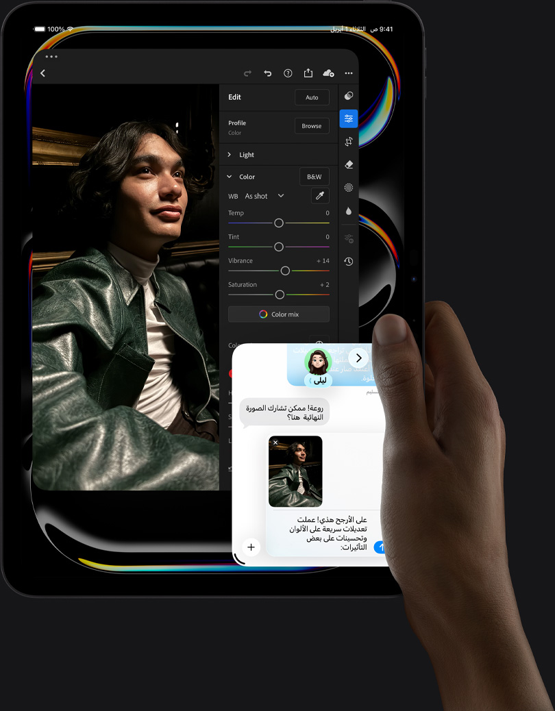 جهاز iPad&nbsp;Pro، الجزء الأمامي الخارجي، الوضع العمودي، لون أسود فلكي، يد يمنى تحمل الجهاز، شاشة تعرض تطبيقاً لتعديل الصور مع صورة لشخص يرتدي زياً أزرق، وأدوات التعديل وخياراته في القائمة اليمنى، وفي الجزء السفلي الأيمن من الشاشة تبدو محادثة iMessage جارية بين المستخدم وشخص آخر لمراجعة الصورة