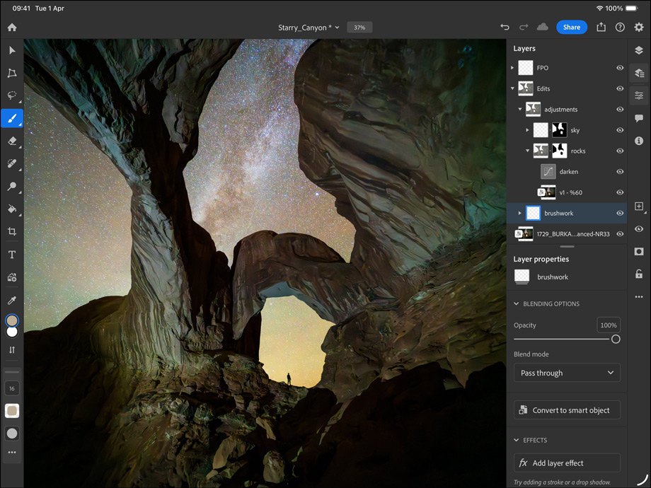 iPad Pro, front exterior, landscape orientation, space black colour, rounded corners, black display bezel, display showing a photograph being edited of a canyon and a star-filled night sky, at right, editing layers, tools and effects visible including brushwork, adjustments and others