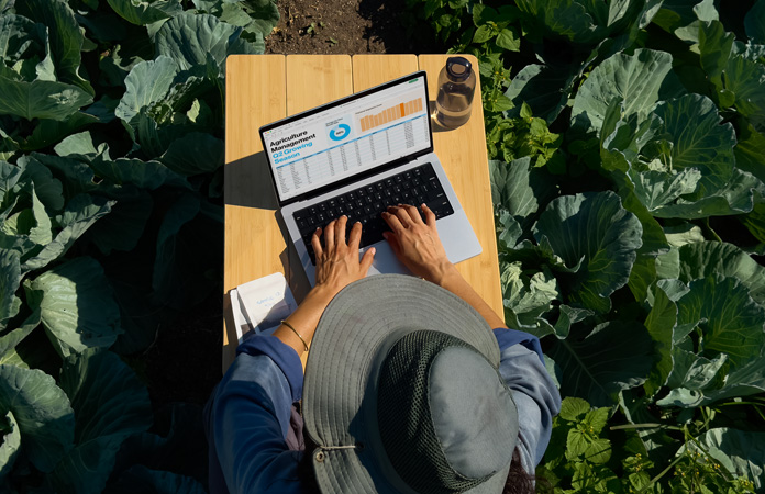 Une personne utilise un MacBook Pro doté d’un écran nanotexturé à l’extérieur, ce qui illustre la réduction des reflets