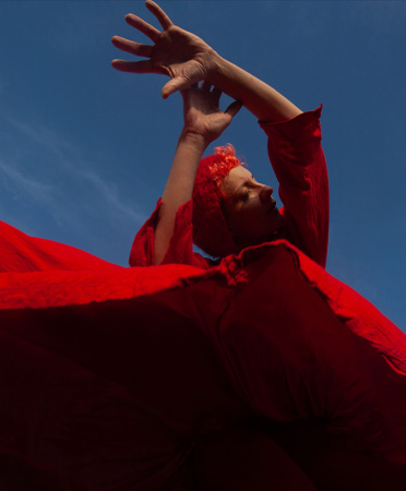 Une personne danse, vêtue d’une robe rouge