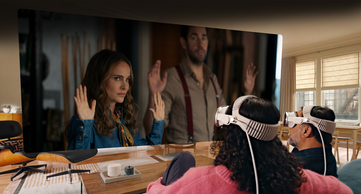 Deux personnes portant un Apple Vision Pro assises côte à côte sur un canapé et regardant le film La fontaine de Jouvence sur un écran s’étendant d’un bout à l’autre de la pièce