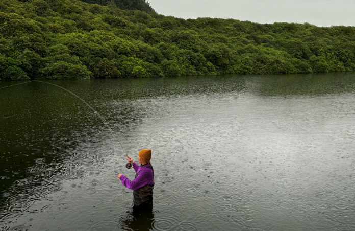 Photo d’une femme qui pêche à la mouche dans un cours d’eau, outil Pixelmator Pro qui supprime un objet non désiré